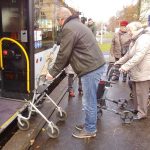 Der Mobilitätstrainer steht mit dem Rollator vor der Tür des Busses und ist einen Schritt nach hinten getreten.